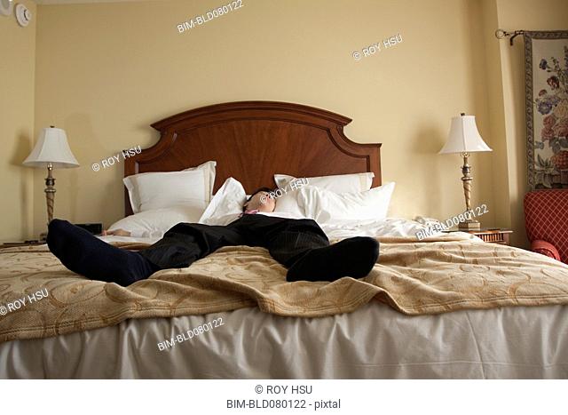 Chinese businessman sleeping in hotel bed