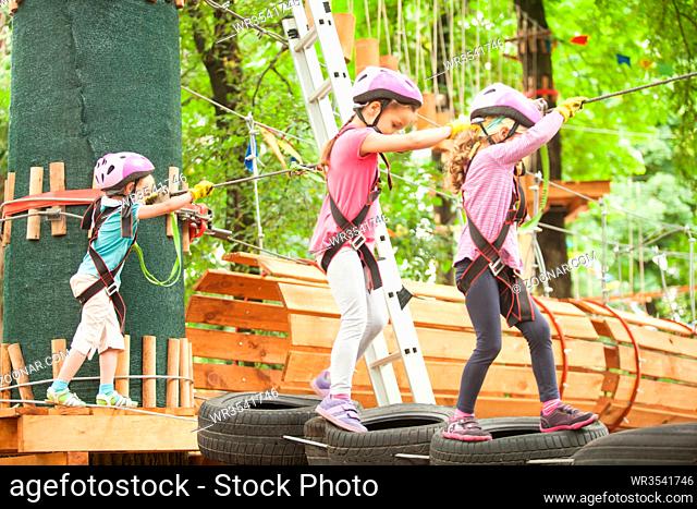 Kids on obstacle course in adventure park in mountain helmet and safety equipment