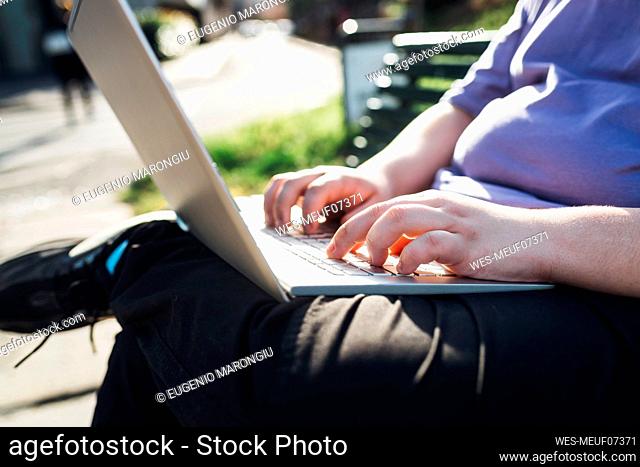 Hands of teenage boy using laptop in park