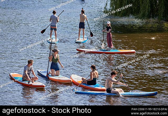 11 June 2023, Hamburg-Winterhude: Stand-up paddlers and rowers enjoy their outing on a canal of the Außenalster in Hamburg-Winterhude on Sunday in summery warm...