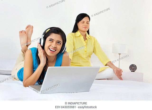 Girl listening to music while mother meditates