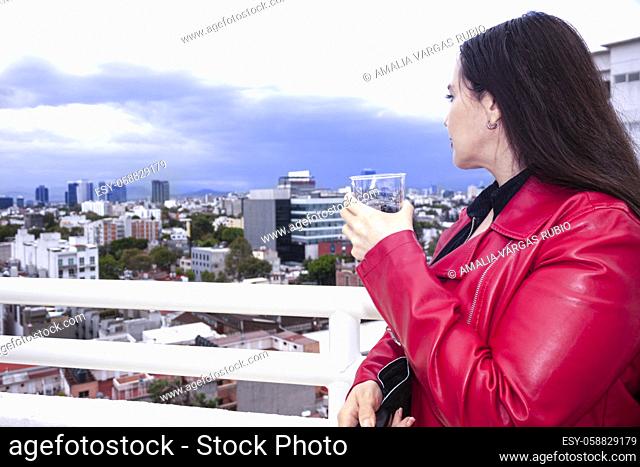 Caucasian woman saying health to the universe with an old fachion glass of whiskey on the rocks in the city