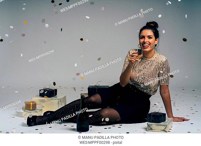 Portrait of young woman dressed for a party, celebrating Christmas with gifts and champagne