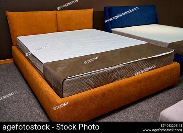 Exhibition of comfortable stylish beds with orthopedic mattresses in the furniture store showroom and square samples of mattresses of different hardness on a...