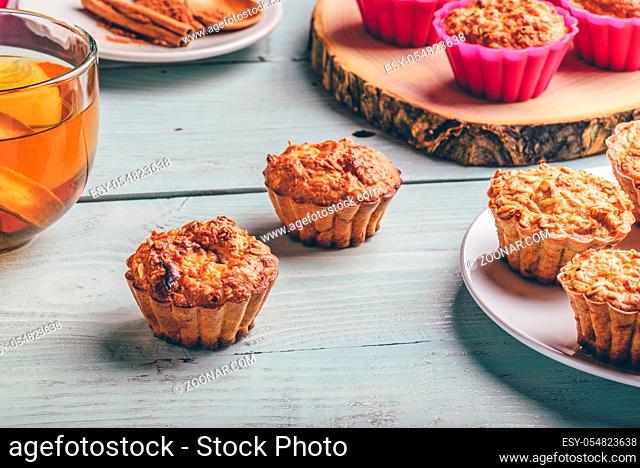 Healthy Dessert. Oatmeal muffins with cup of green tea over light wooden background