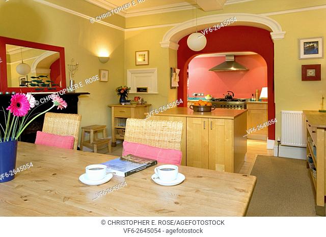A large vibrantly decorated dining room with a small galley kitchen beyond. Editorial Use Only