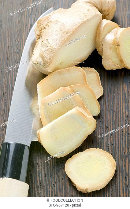 Ginger root, partly sliced, with Asian knife