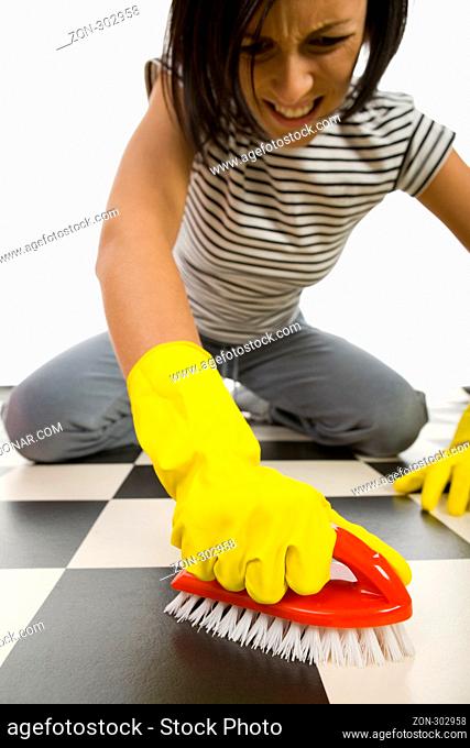 Young woman in yellow rubber gloves kneeling and scrubs the floor. Focused on hand in glove with brush. Front view. White background