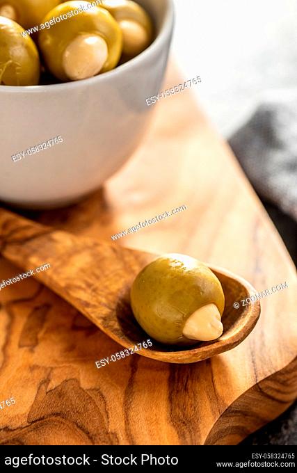 Pitted green olive stuffed with almonds on wooden spoon