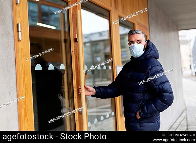 Man wearing face mask opening door
