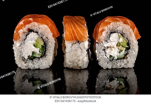 Three pieces of sushi rolls Philadelphia. Black background. Reflection
