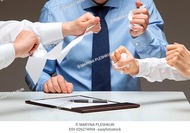 Business people cruelly tearing documents, gray background