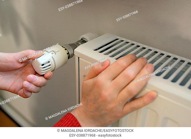 Woman Adjusting Thermostat On Radiator