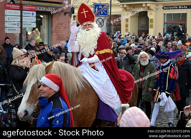 09 December 2023, Brandenburg, Potsdam: The historic Dutch Santa Claus figure Sinterklaas rides into Potsdam's Dutch Quarter on a white horse - as is customary...