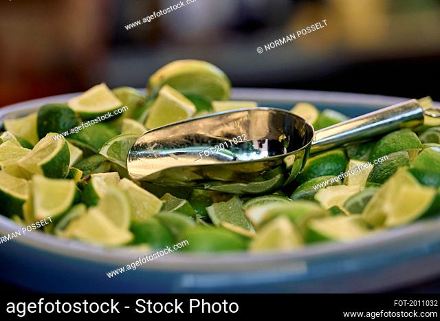 Close up fresh lime wedges in bowl with scoop