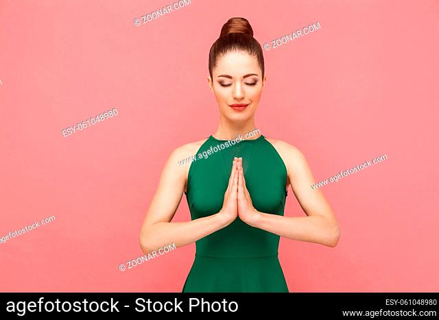 Spiritual practice. Woman closed eyes, doing meditation, mudram peace. Expression emotion and feelings concept. Studio shot, isolated on pink background
