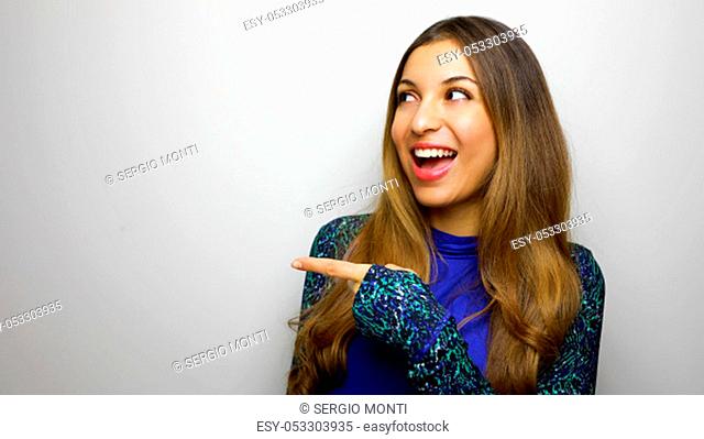 Beautiful sporty female teenager shows place for fitness, indicates aside with finger at upper left corner isolated over white background. Copy space