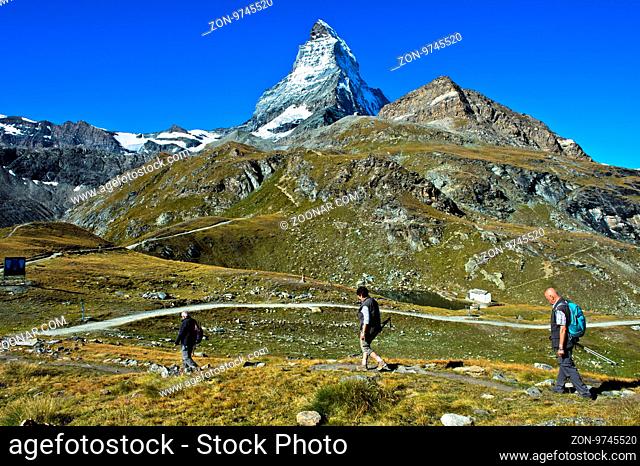 Drei Touristen im Wandergebiet Zermatt, hinten Schwarzsee und Matterhorn, Zermatt, Wallis, Schweiz / Three tourists in the hiking area around Zermatt