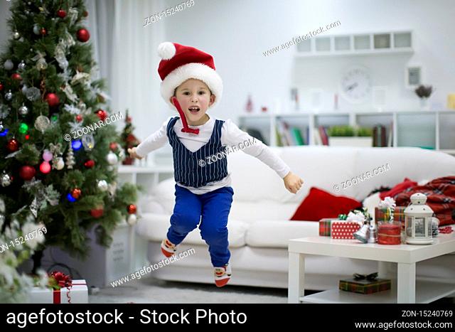 The boy is happy with the New Year. Happy child on christmas. Emotions overwhelm. A boy in a cap of Santa Claus jumps up.The New Year has come