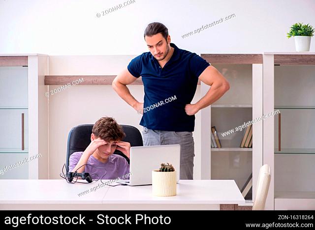 Father and schoolboy playing computer games at home