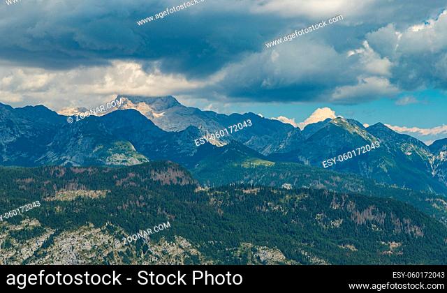 A picture of the Triglav peak, under the clouds, surrounded by the Triglav National Park