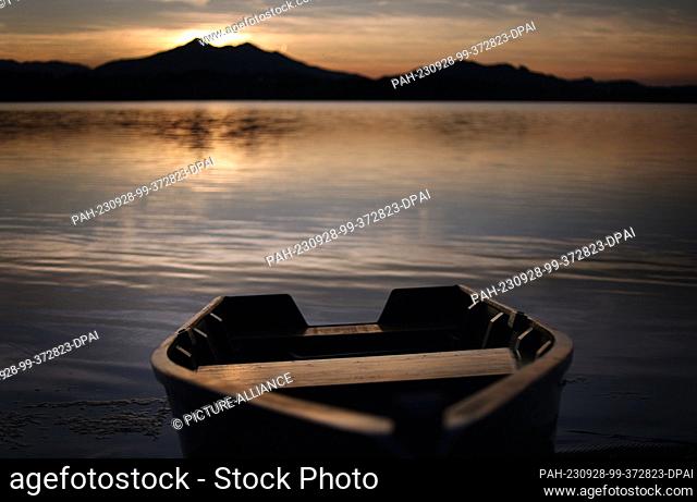 28 September 2023, Bavaria, Füssen: A rowing boat lies in the sunset on the shore of the Hopfensee lake, located on the edge of the Alps