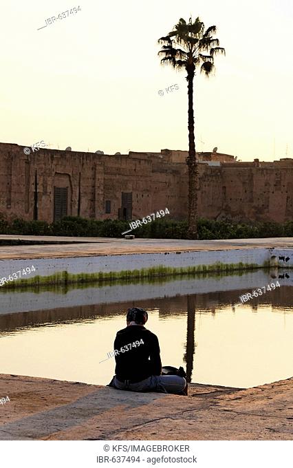 Female tourist resting at the edge of a water basin, historic inner courtyard of Palais EL Badi, Marrakech, Morocco, Africa