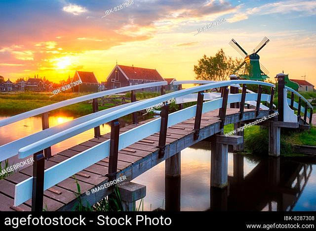 Netherlands rural scene, bridge over canal and windmills at famous tourist site Zaanse Schans in Holland on sunset with dramatic sky Zaandam, Netherlands