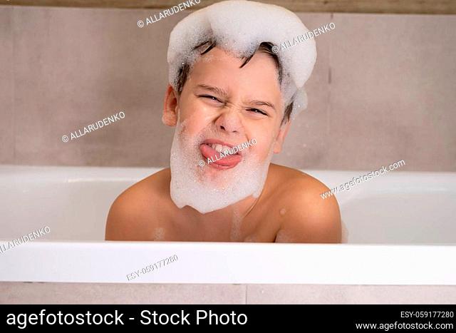 Closeup portrait of funny boy playing with water and foam in bathroom Cute happy child bathe and makes funny faces healthy childhood