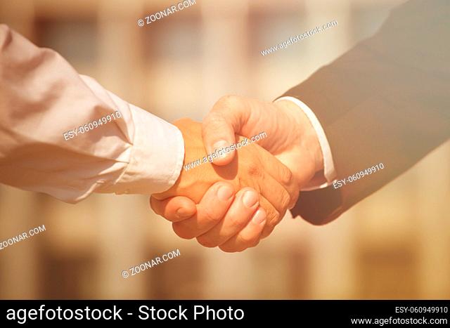 Business handshake, the deal is finalized between two enterprises. Man in black suit and woman in white one have signed the agreement. Toned image