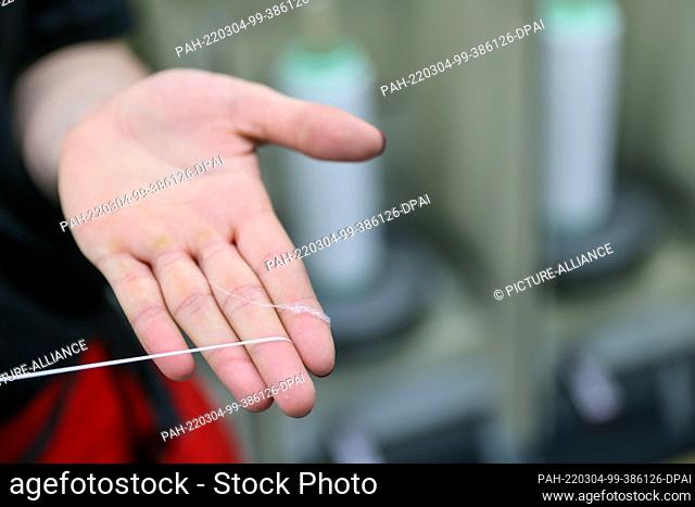 01 March 2022, Saxony, Flöha: An employee shows the raw white before it is twisted into yarn in the twisting mill of OTEX Textilveredlung GmbH