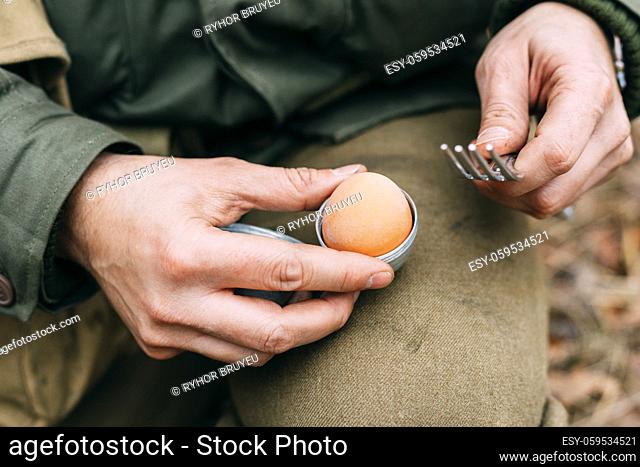 Re-enactor Dressed As Soldier Of USA Infantry Of World War II Holds Egg Holder In Hands During Breakfast. Close Up