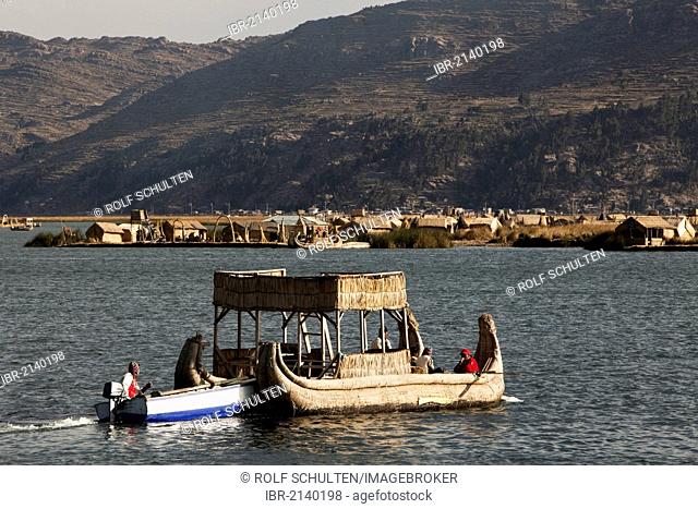 Traditional reed boat being pushed by a motorized boat, floating islands of the Urus on Lake Titicaca, constructed by the totora reeds growing there, Puno, Peru