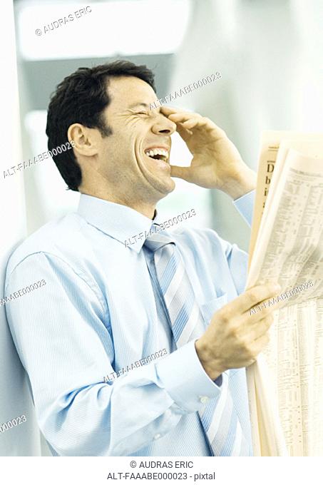 Businessman holding newspaper and laughing