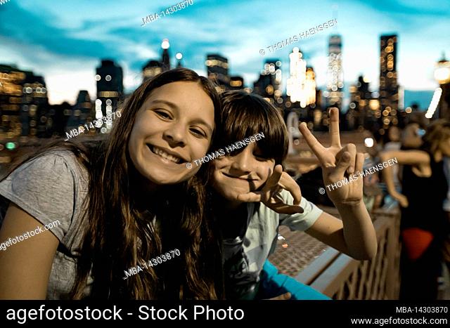 Brooklyn Bridge, New York City, NY, USA, Young girl and boy enjoying the evening on Brooklyn Bridge over East River 14 years old caucasian teenager girl and 12...