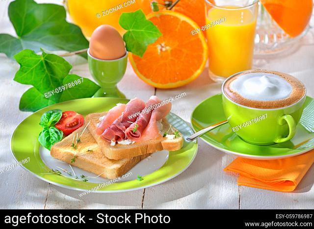 Frühstück mit Schinkentoast und Ei sowie einer Tasse Cappuccino - Breakfast with ham toast, a boiled egg and a cup of cappuccino