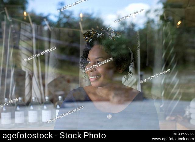 Smiling female shop owner at window