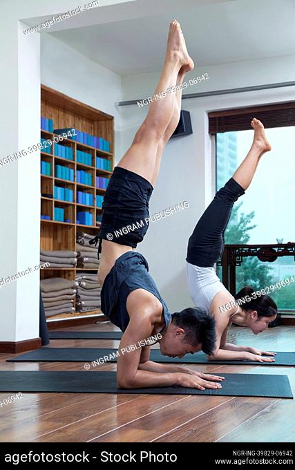 Two people with legs raised doing yoga in a yoga studio
