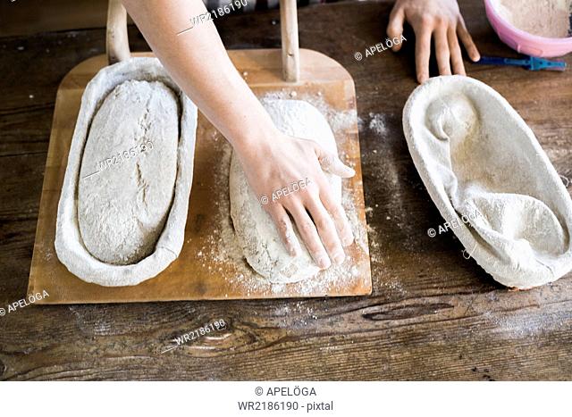 High angle view of baker's hands with dough at table in bakery