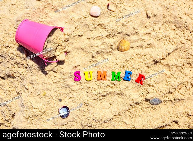word summer from multicolored wooden letters on sand, top view