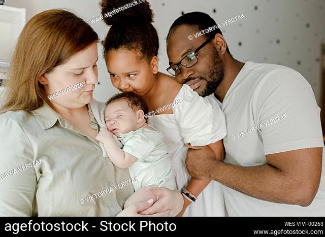 Smiling father and mother embracing daughters at home
