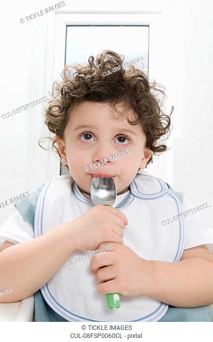 A boy sucking a spoon