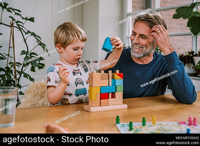 Father watching son playing with puzzle while sitting at home