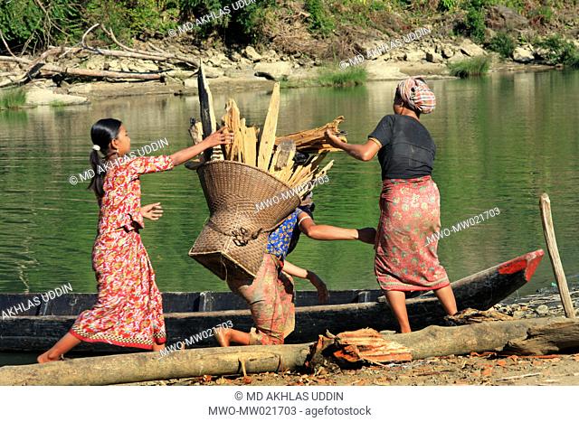 A woman with a heavy load of fire wood is being helped to get on a boat Thanchi in Bandarban, Bangladesh December 2, 2009