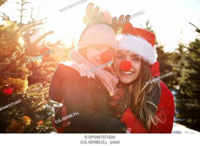 Girl and mother in christmas tree forest with red noses, portrait