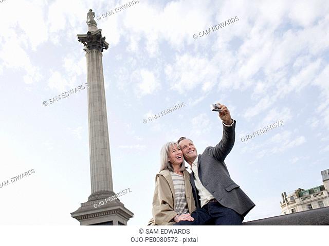 Couple taking self-portrait with digital camera under monument