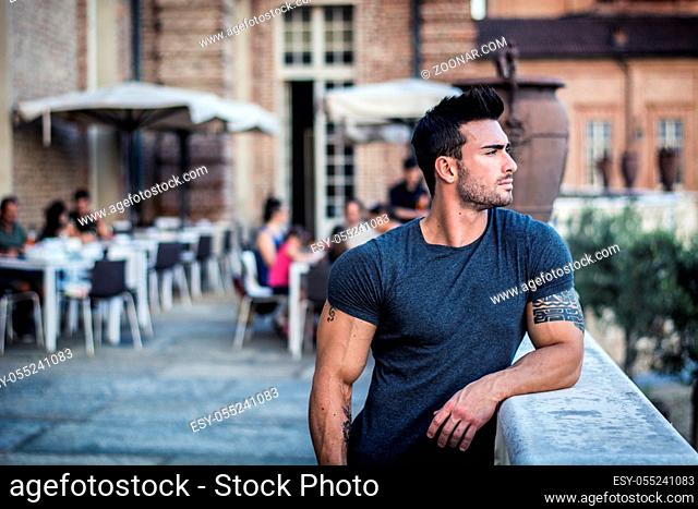 Handsome muscular man with tattoo posing in European city center, Turin, Italy