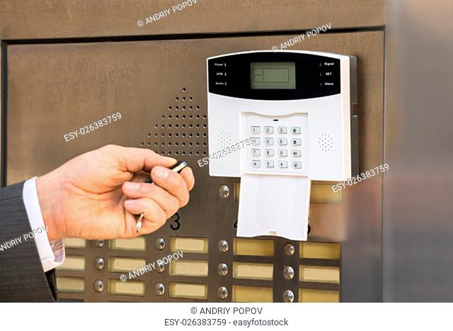 Close-up Of Businessperson Hand Using Remote Control For Operating Door In Security System