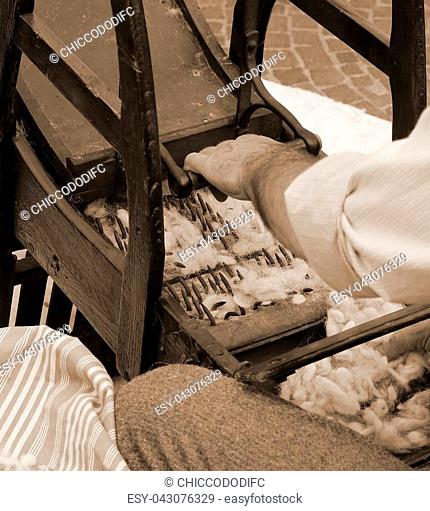 Elder carder while carding wool with old wooden machine to make the cushions and mattresses sepia toned