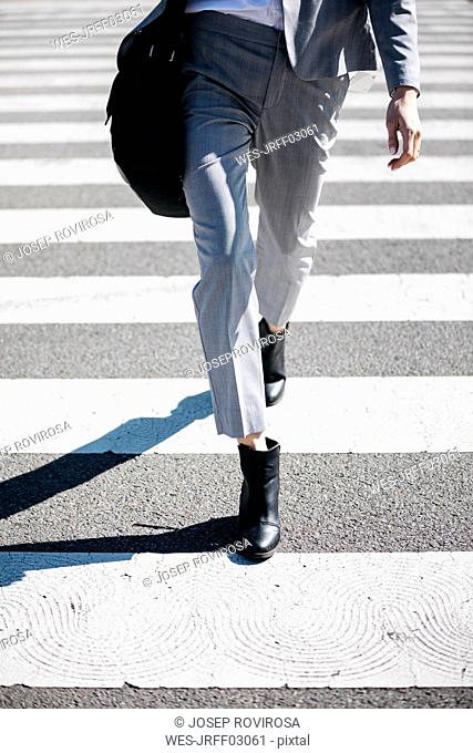 Business woman walking on zebra crossing, low section